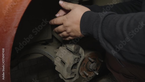 Professional auto mechanic unscrewing a bolt on a car brake caliper with a wrench during a maintenance service in a repair shop, ensuring vehicle safety and performing necessary repairs