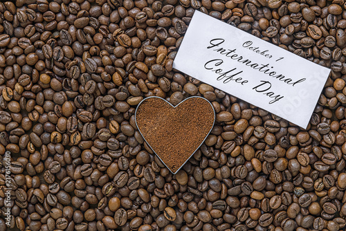 International Coffee Day concept with roasted coffee beans, heart shaped ground coffee and greeting card.