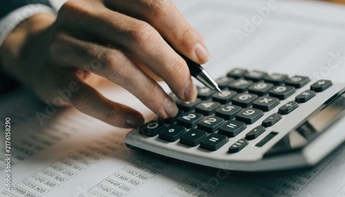 Obraz na płótnie Person's hand using a calculator over financial documents