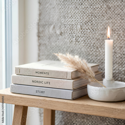 Cozy Nordic home decor with stack of books candle and dried grass on wooden bench