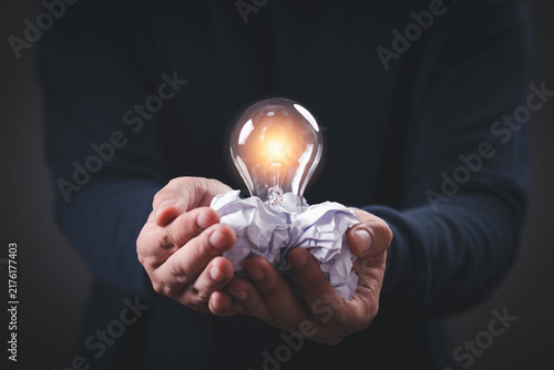 Foto Creative innovation concept featuring a glowing light bulb held above crumpled paper, symbolizing fresh ideas, inspiration, brainstorming, problem solving, imagination, invention, business creativity