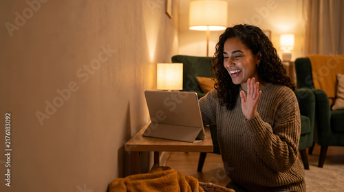 Woman waving during video call from hotel bedroom with tablet