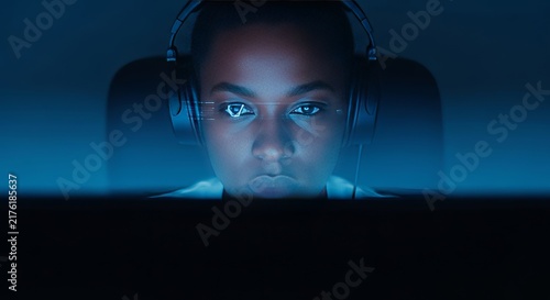 Deep complexion illuminated by the soft blue glow of a monitor in a quiet room, capturing a moment of intense focus and digital reflection, working, office, silent