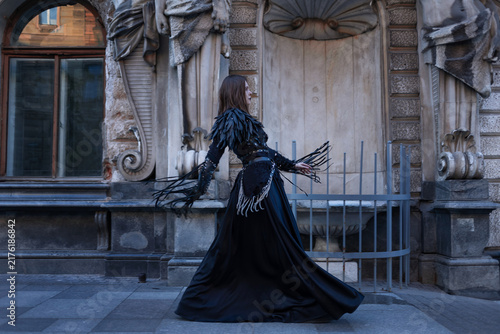 Bild auf Leinwand Woman in a long black gown turns on the pavement, flowing skirt and leather frin