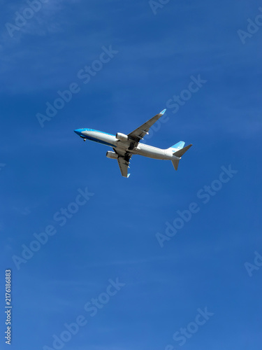 Modern commercial passenger airplane flying through a clear vibrant blue sky, low-angle view with ample copy space for travel stock.