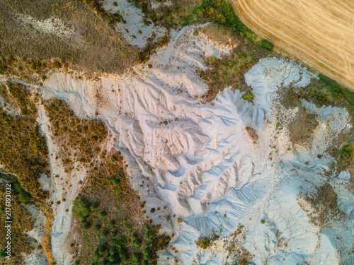 Bild auf Leinwand Aerial view of the pale eroded badlands and clay ravines meeting golden fields in the Spanish Pyrenees foothills Aragon Spain an abstract landscape of geology and time