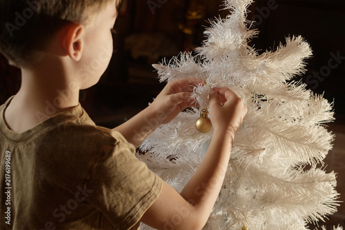 Foto Child decorating white Christmas tree with Christmas decoration