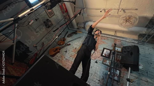 Young Asian Spiritual Leader Preaching Sermon Making Dramatic Theatrical Reaching Gesture With Microphone On Stage In Cozy Cafe Church Gathering Low Dutch Angle Handheld Authentic Lifestyle Shot