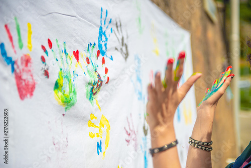 Hands with colorful paint leaving prints on a white cloth during an art event
