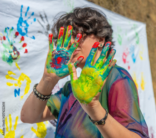 Hands with colorful paint leaving prints on a white cloth during an art event