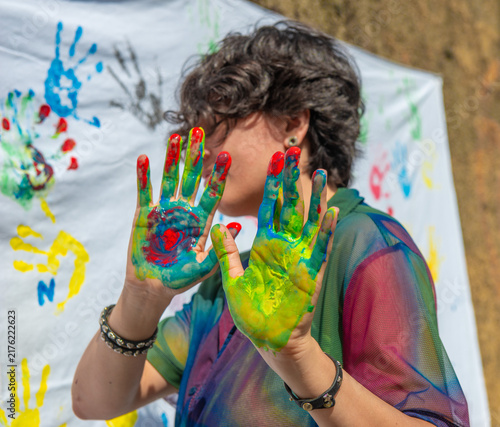 Hands with colorful paint leaving prints on a white cloth during an art event
