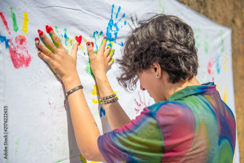 Hands with colorful paint leaving prints on a white cloth during an art event