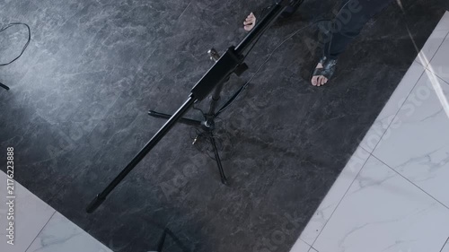 Unrecognizable male podcast host taking black headphones from microphone stand preparing for true crime audio broadcast interview in modern digital media studio top down high angle authentic shot