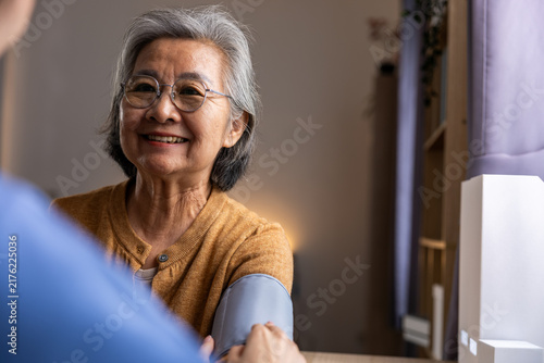 Elderly Asian woman smiling during home consultation with healthcare worker