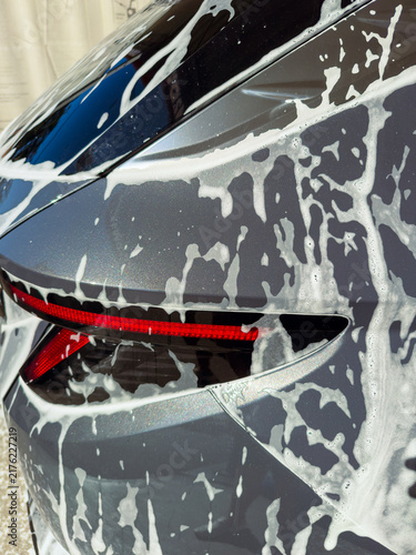 Quadro su tela Car washing process takes place at a detail shop with soap covering the rear of