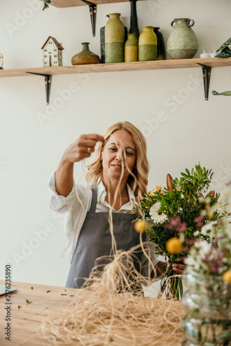 Fotografie Florist woman preparing flower bouquet with raffia