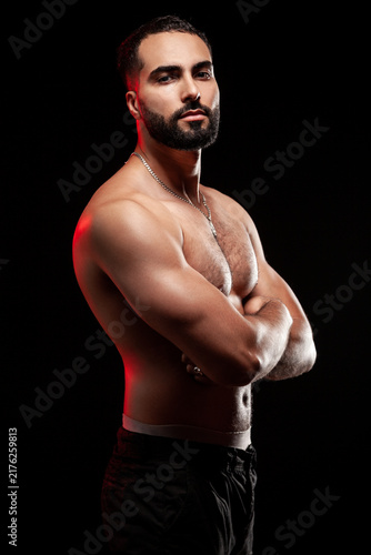 Obraz na płótnie Strong guy standing sideways showing massive bicep and triceps with crossed arms