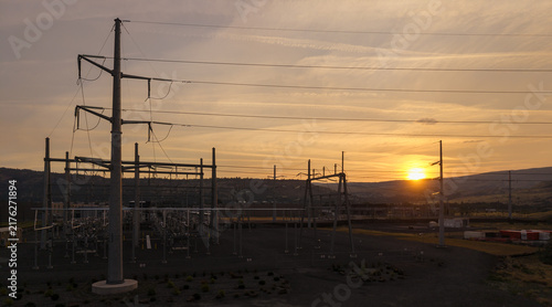 Aerial view of The Dalles data center power substation with electrical towers and transmission lines silhouetted against a golden sunset sky in The Dalles, Oregon, United States.
