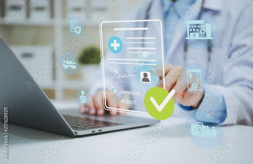 Foto Doctor reviewing digital health insurance approval on laptop managing patient eligibility medical claims electronic records reimbursement and healthcare administration