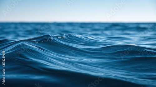 Waves roll softly on deep ocean blue water with a clear sky above, providing a simple backdrop for various designs