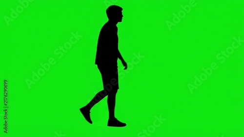 Silhouette of a casual man walking across the screen on a green screen chroma key background