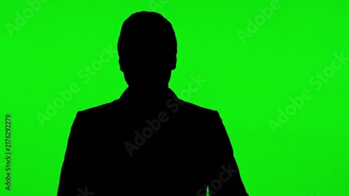 Silhouette of a businessman waving and presenting with hand gestures on a green screen chroma key background