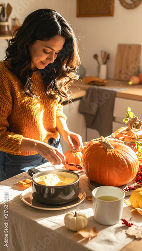 Thanksgiving & Autumn Wellness: Happy lady hand peels an orange pumpkin for festive autumn feast
