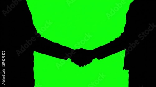 Silhouette of two business people shaking hands on a green screen chroma key background