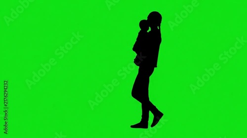 Silhouette of a mother walking across the screen and holding her baby on a green screen background