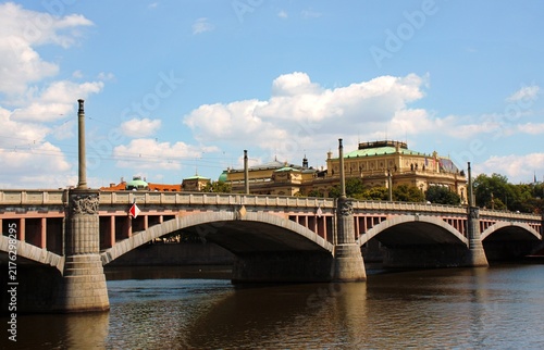 Принти на полотні Prague, Czech Republic: Historic bridge over Vltava River with ornate architecture and city landmarks under blue summer sky