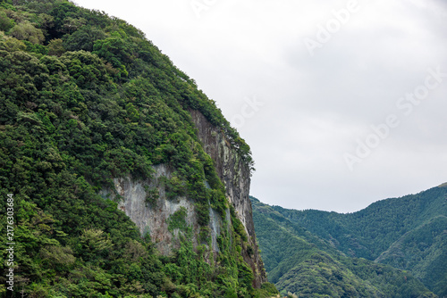 Fototapeta 深い緑の木々に覆われた切り立った断崖絶壁と連なる山並み