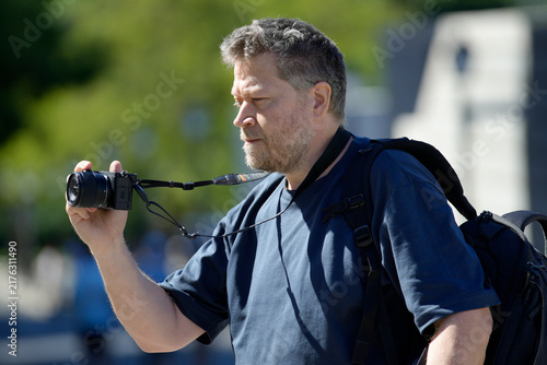 Man enjoying hobby photography with mirrorless camera outdoors