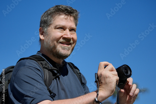 Man with camera smiling enjoying photography outdoors
