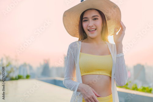 Принти на полотні Portrait of cheerful smiling young woman wearing sun hat enjoying golden hour sunset at luxury rooftop, radiating joyful optimism, vitality, happiness, freedom, and vacation vibes