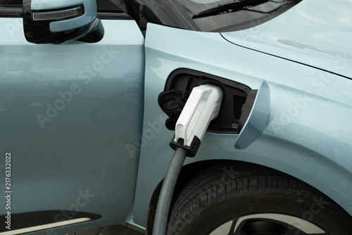 White electric car charger plugged into a modern vehicle