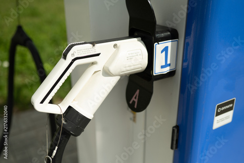 White EV charging plug nozzle docked at a public station terminal