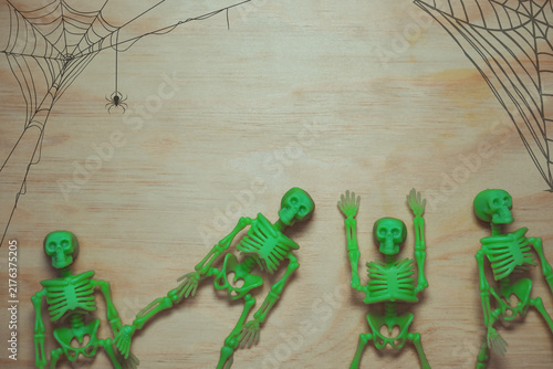 Foto Four green skeleton toys arranged on a wooden surface, surrounded by illustrated spider webs and a spider, suggesting a Halloween theme