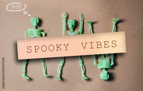 Foto Three glowing skeleton figures arranged on a brown background with a 'Spooky Vibes' sign, suggesting a Halloween theme