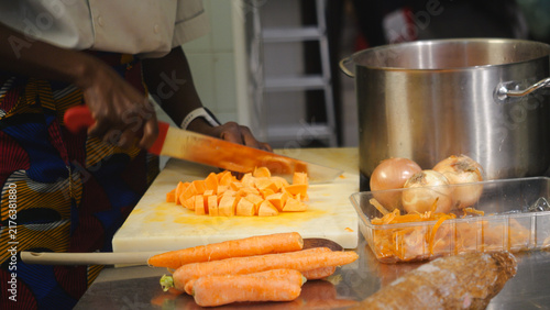 фотографія Chef's hands dicing sweet potatoes and carrots on a cutting board in a professio