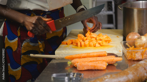 Foto Chef's hands dicing sweet potatoes and carrots on a cutting board in a professio