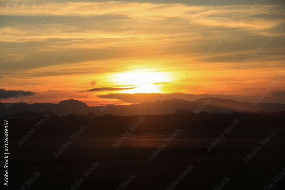 Fototapeta premium Golden sun setting behind layered mountain silhouettes over Bogota