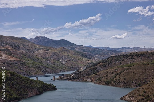 Reservoir bridge spanning mountain valley under blue sky