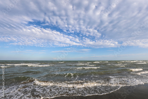 Foto Wavy sea shore under bright blue sky with white fluffy clouds at Barricata beach