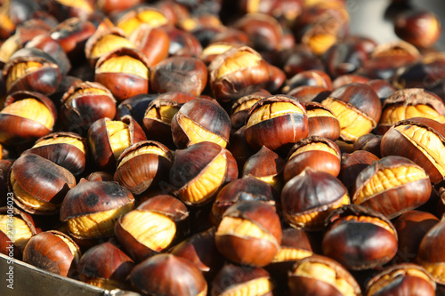 Freshly roasted chestnuts with cracked shells displayed on a street food stall