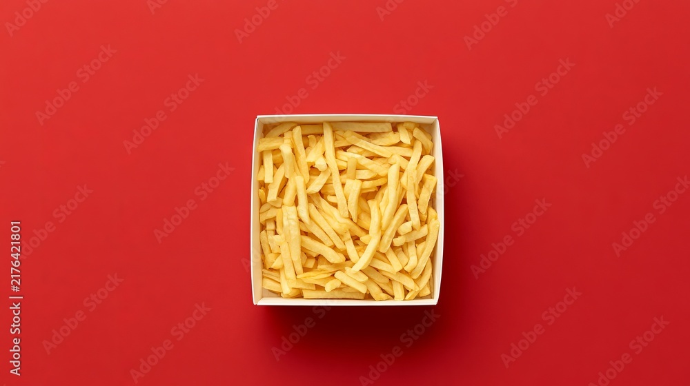 Obraz premium Crispy golden fries in white box, served as fast food snack on bright red surface