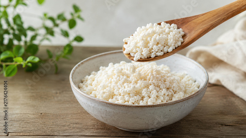 Spoonful of Rice Koji Over Bowl on Rustic Wooden Table
