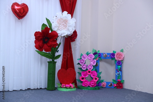 The set includes a decorative number eight frame for March 8th events. photo booth decorations with giant handcrafted paper flowers and a red heart balloon for International Women's Day celebrations.