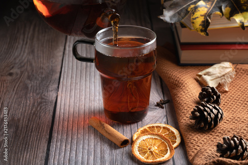 Foto Hot tea pouring into a glass mug with orange and cinnamon