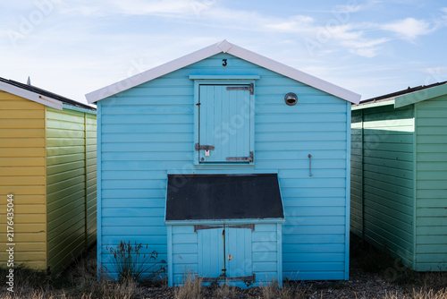 Obraz na plátně Blue beach hut with white trim and shuttered doors in a row of colorful seaside