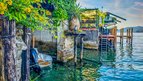 Traditional Italian lakeside atmosphere with a motorboat stored in a waterside boathouse garage, capturing the charm of lakefront living and boating on the Italian Lakes district